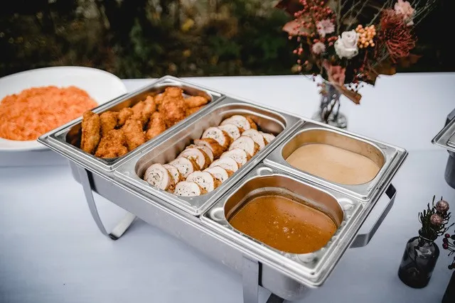 Catering-Buffet im Detail: Paniertes, gefüllter Braten, hausgemachte Saucen und Salat in Chafing-Dishes.