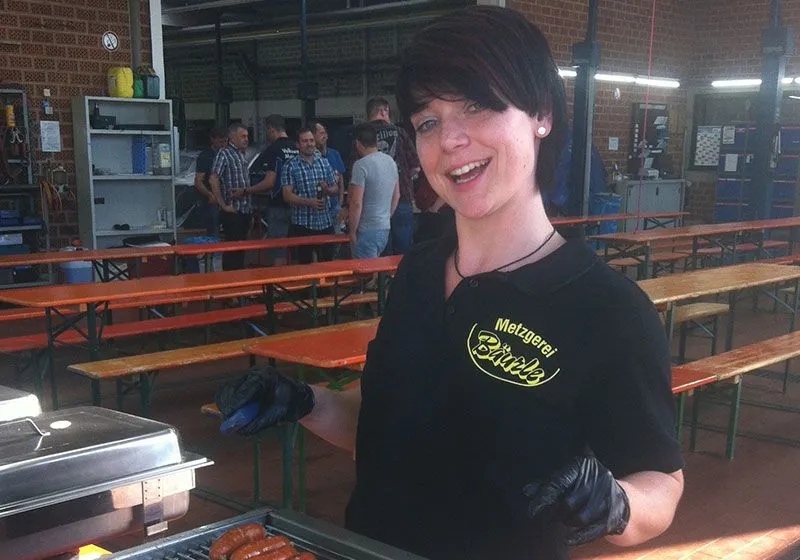Eine Mitarbeiterin der Metzgerei Bäurle serviert frisch Gegrilltes bei einem Catering-Einsatz.