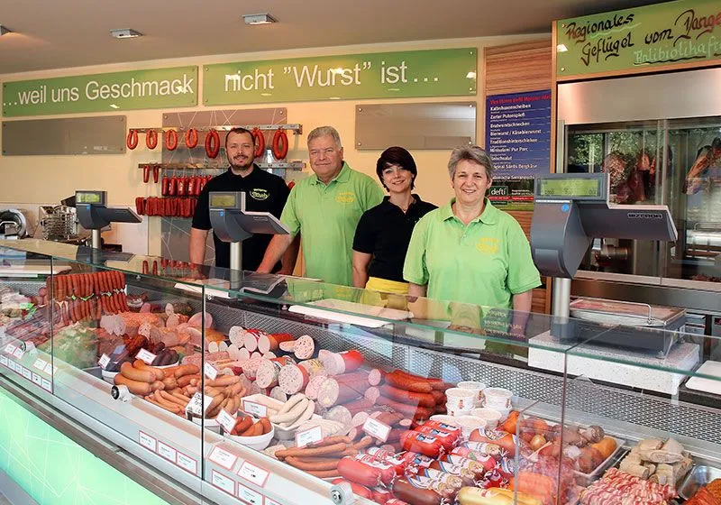Das vierköpfige Team der Metzgerei Bäurle hinter der gut gefüllten Wursttheke. An der Wand steht der Spruch ‚…weil uns Geschmack nicht Wurst ist…‘.